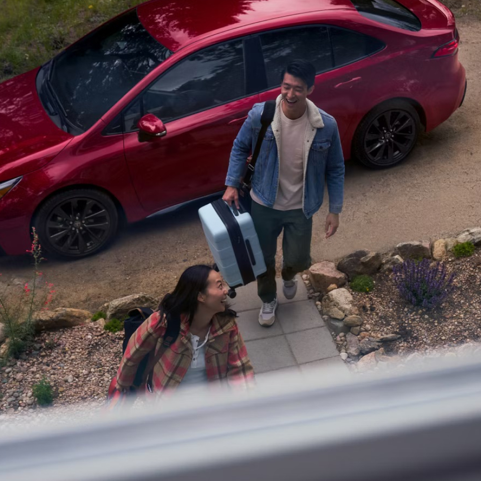 People walking away from 2025 Corolla with luggage. 